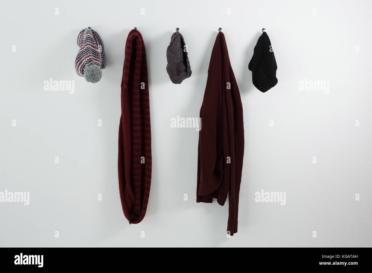 Warm clothings hanging on hook against wall Stock Photo