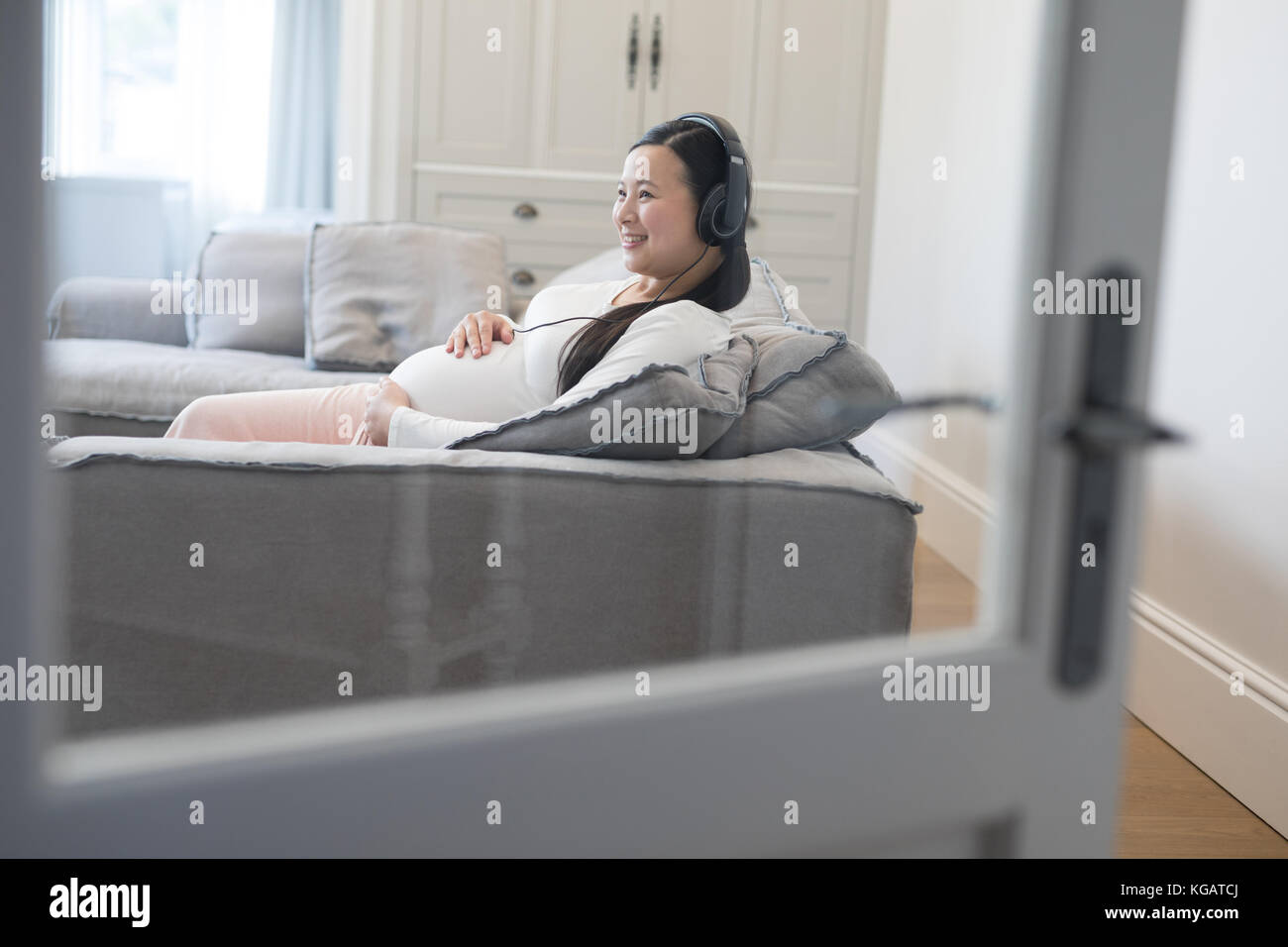 Pregnant woman listening music on headphones at home Stock Photo - Alamy
