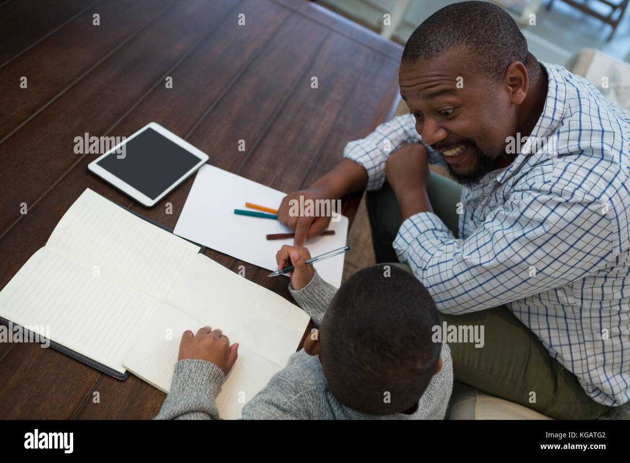 Father helping his son with homework in living room at home Stock Photo ...