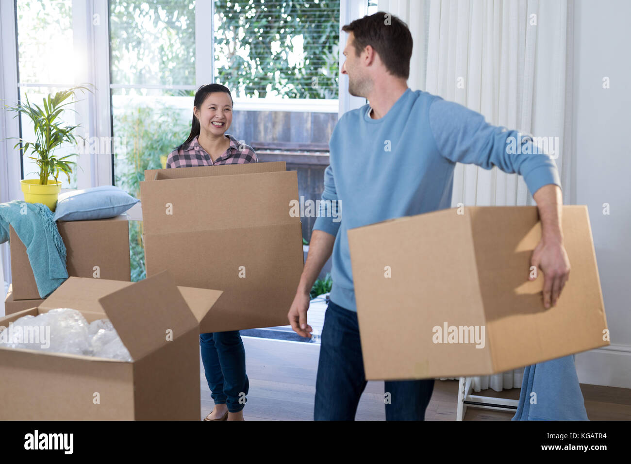 Happy couple carrying big cardboard box at new home Stock Photo