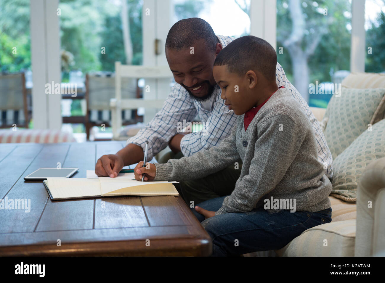 Father helping his son with homework in living room at home Stock Photo ...
