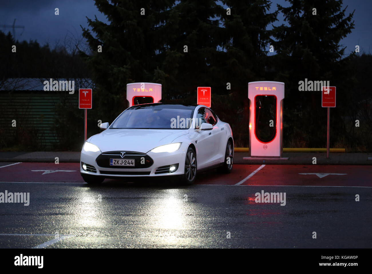 PAIMIO, FINLAND - NOVEMBER 14, 2015: Tesla Model S electric car arrives at the Paimio Tesla Supercharger station at night for charging. Tesla Supercha Stock Photo
