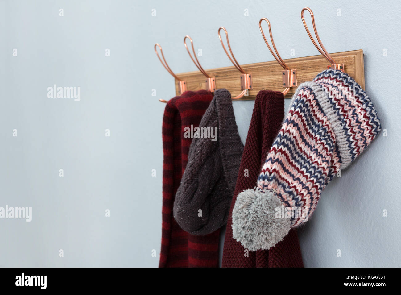 Warm clothings hanging on hook against wall Stock Photo