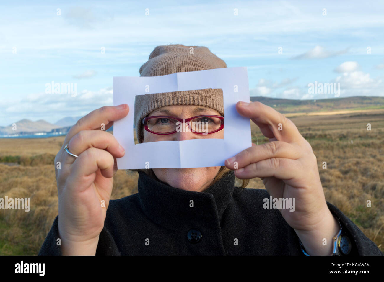 Woman artist framing scene with paper viewfinder Stock Photo