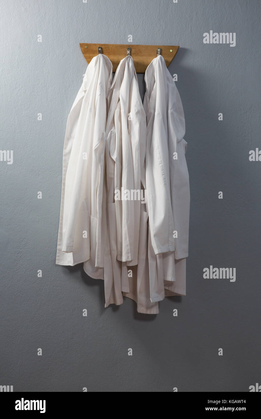 Laboratory coat hanging on hook against wall Stock Photo