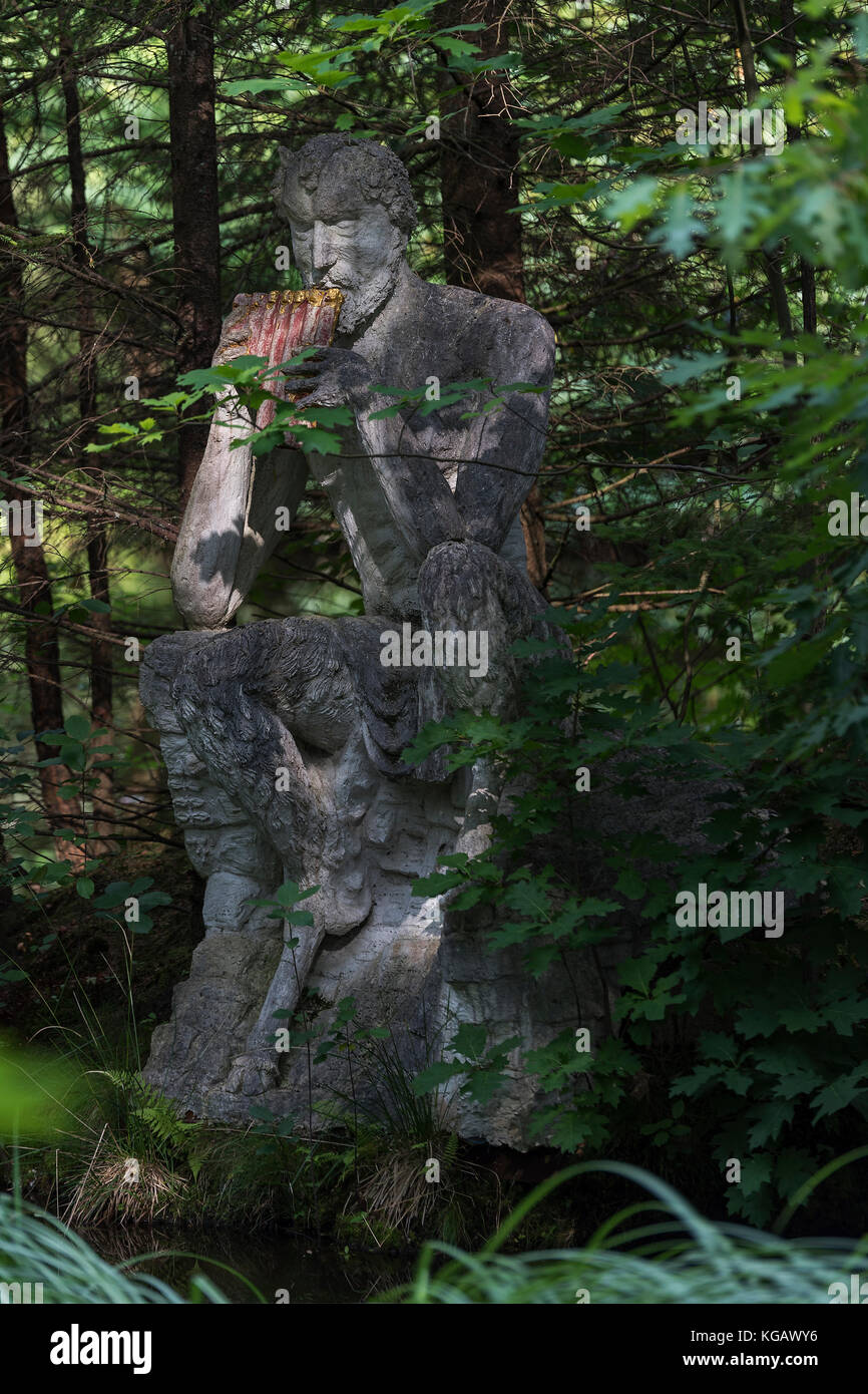 Panskulptur im Park der Iserhatsche in Bispingen auf einem Stein sitzend am Rande des Waldes mit Licht und Schatten Stock Photo