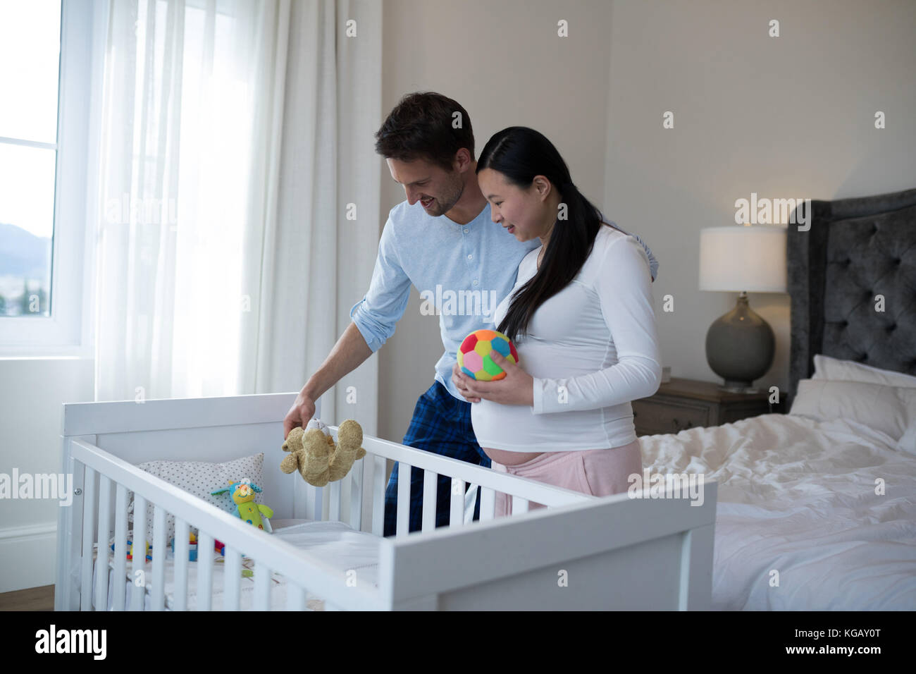 Couple arraigning toys in cot at home Stock Photo