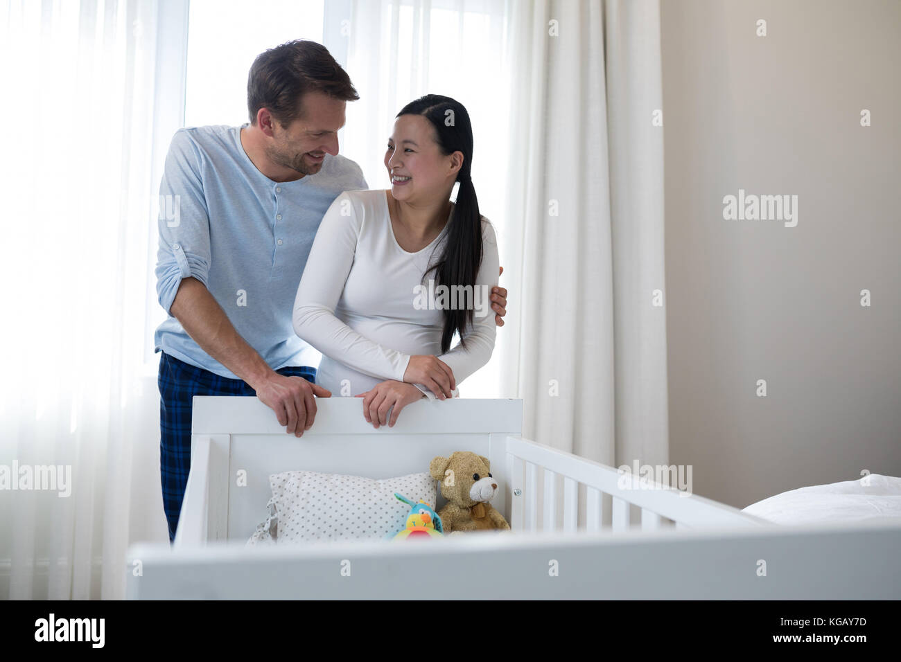 Happy couple standing near cot at home Stock Photo