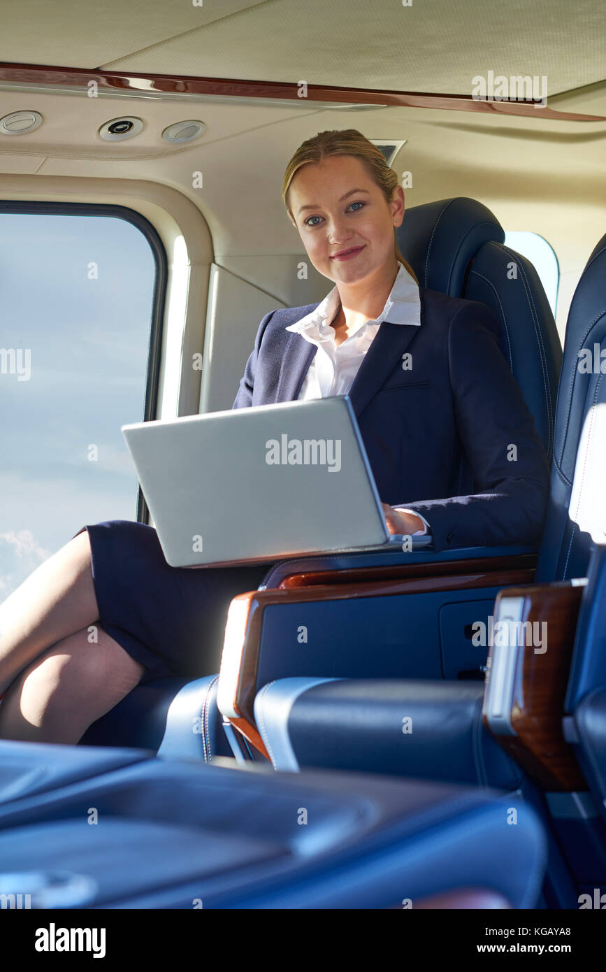 Portrait Of Businesswoman Working On Laptop In Helicopter Cabin During Flight Stock Photo