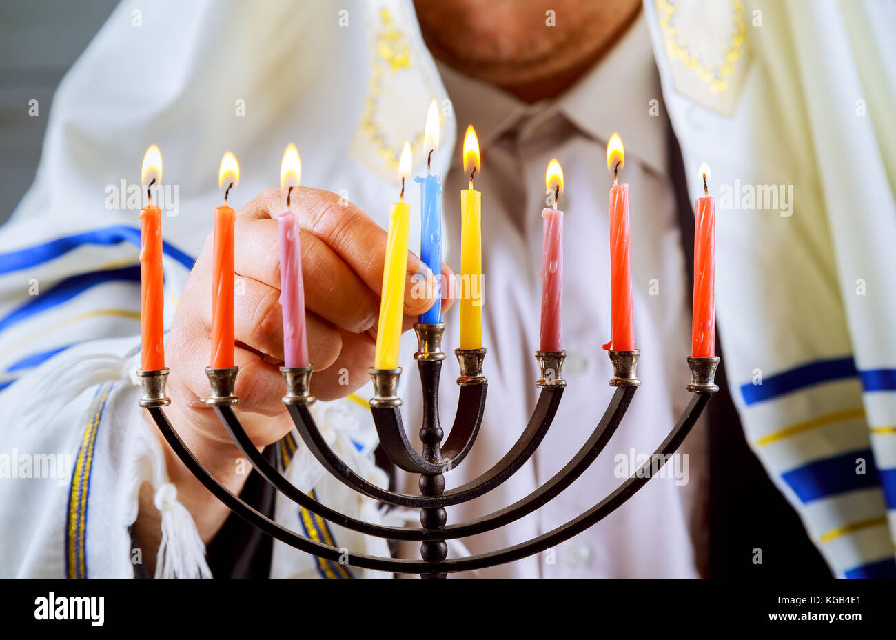 Jewish candle lights male hand lighting candles in menorah on table served for Hanukkah Stock