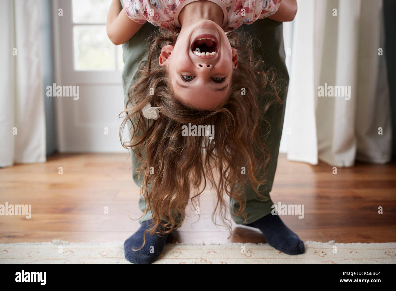 Girl being held upside down by her dad at home, low section Stock Photo