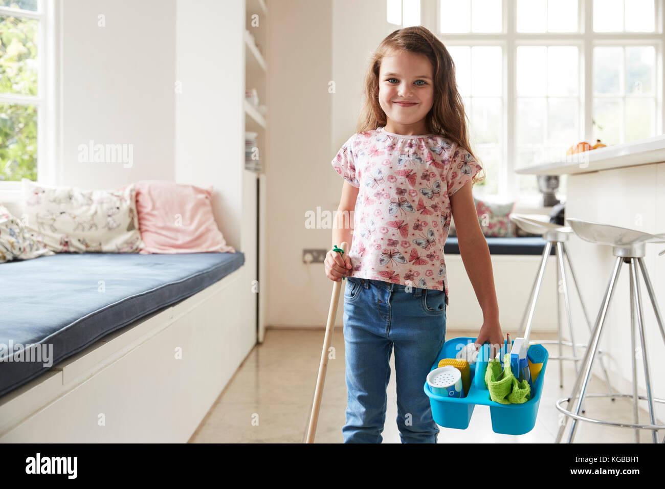 Young girl standing at home with broom and cleaning products Stock Photo