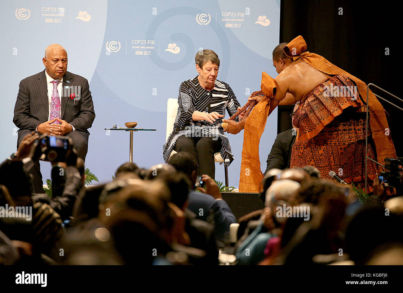Der COP 23 Präsident und Premierminister der Fidschi Inseln, Frank Bainimarama (l) beobachtet am 06.11.2017 in Bonn (Nordrhein-Westfalen) zum Auftakt der Weltklimakonferenz die Überreichung eines Geschenkes an Umweltministerin Barbara Hendricks (M) durch einen Vertreter der Fidschi Inseln. Die Weltklimakonferenz COP23 findet 06. bis 17. November 2017 in Bonn statt The COP23 president and prime minister of the Fiji Islands Frank Bainimarama(L) observes handing out of the present for the climate minister Barbara Hendrick(M)by the representative of the Fiji Islands in Bonn, Germany, 6 November Stock Photo