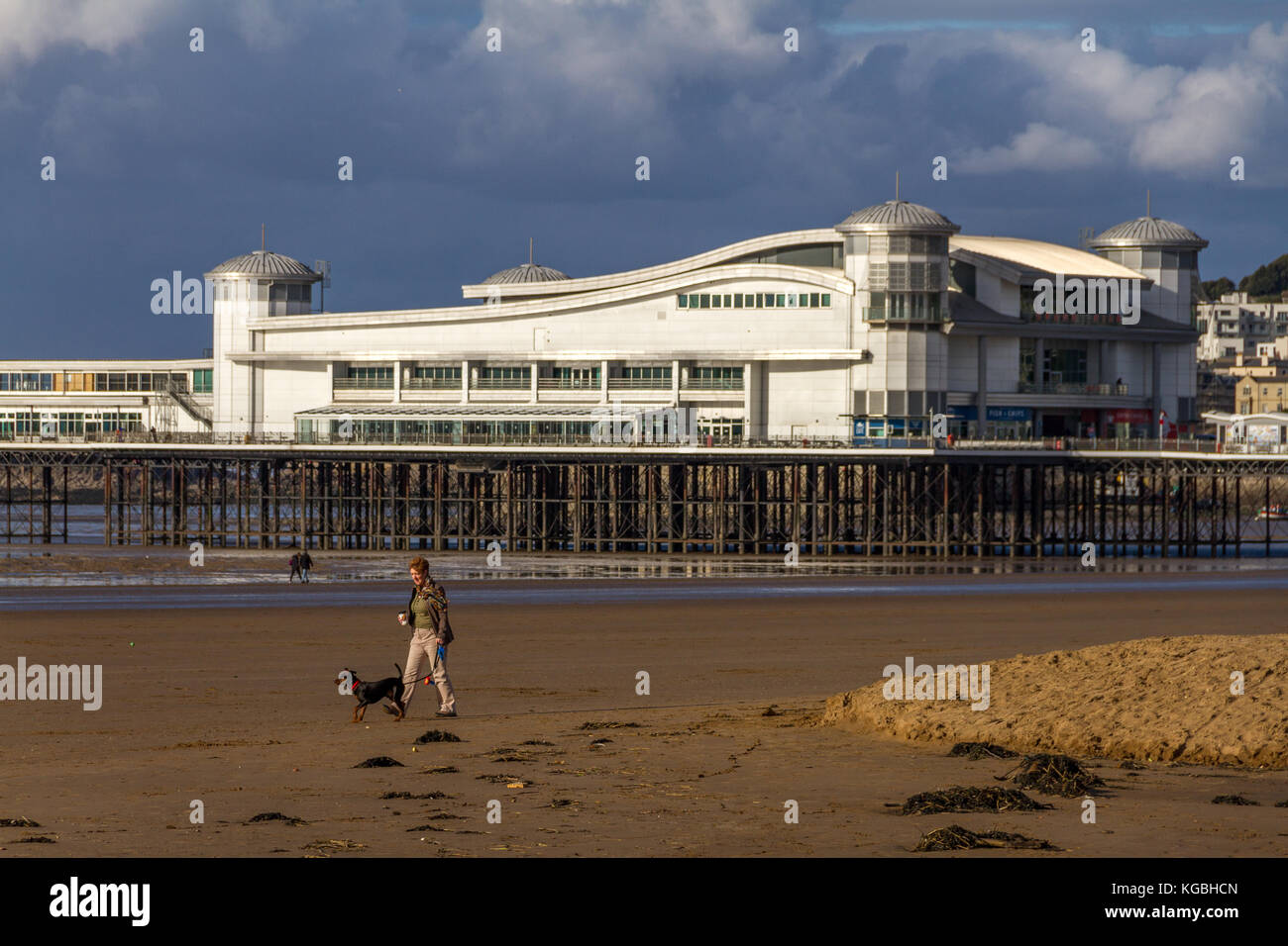 Woman walking her dog along the beach next to the Grand Pier on a changeable November afternoon, Weston-Super-Mare, Somerset, Avon, England, UK. 06th Nov, 2017. Stock Photo