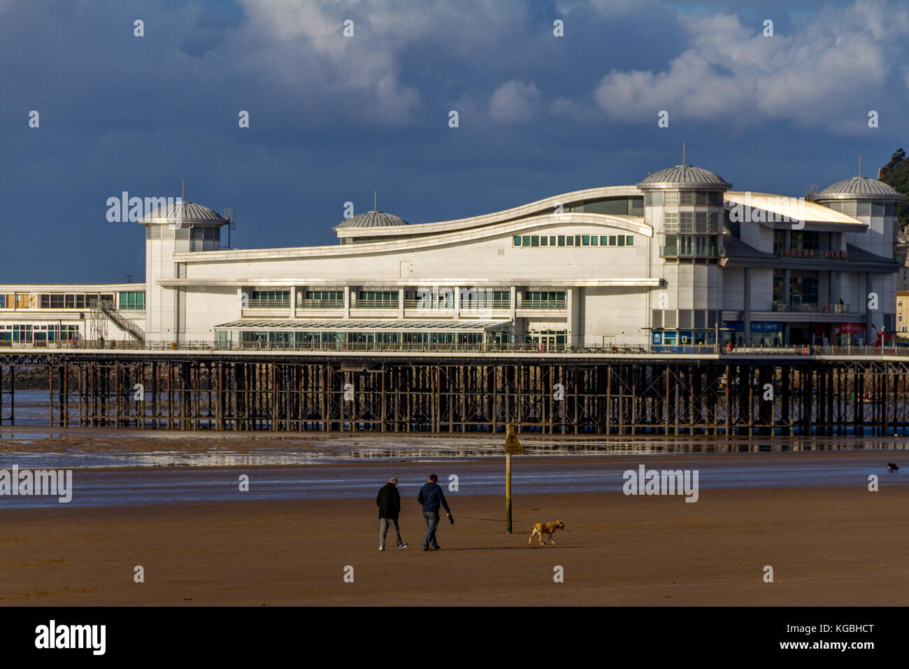 Woman walking her dog along the beach next to the Grand Pier on a changeable November afternoon, Weston-Super-Mare, Somerset, Avon, England, UK. 06th Nov, 2017. Stock Photo