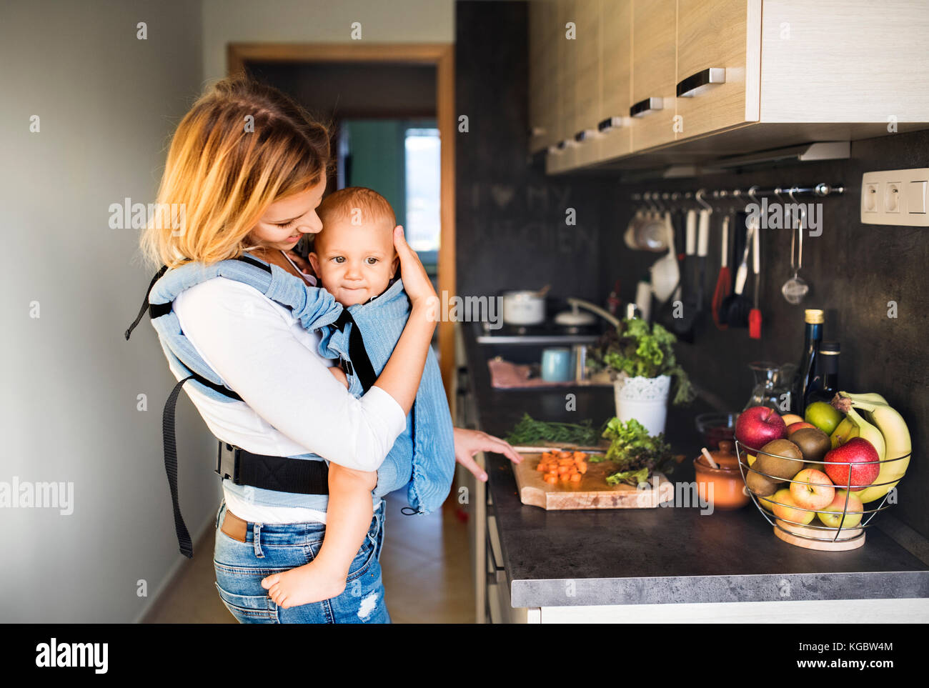 Young mother with a baby boy doing housework. Stock Photo