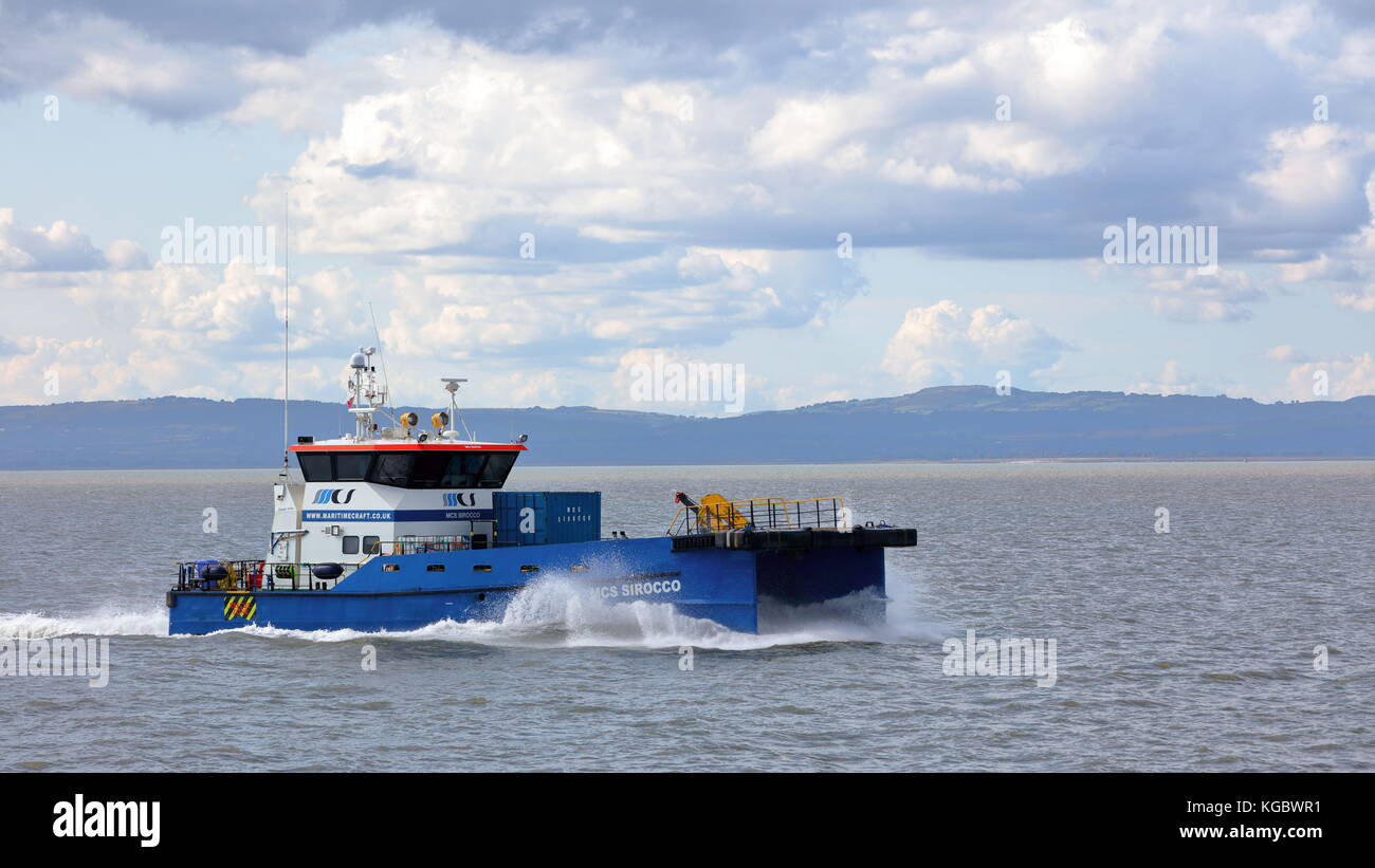 Twin hulled windfarm support vessel MCS Sirocco (Crew Boat) powering up the Bristol Channel to Avonmouth with Welsh coast backdrop Stock Photo