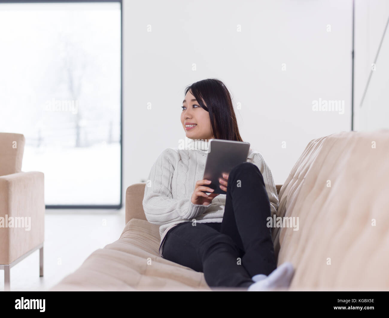 young happy asian woman sitting on sofa using Digital Tablet Stock ...