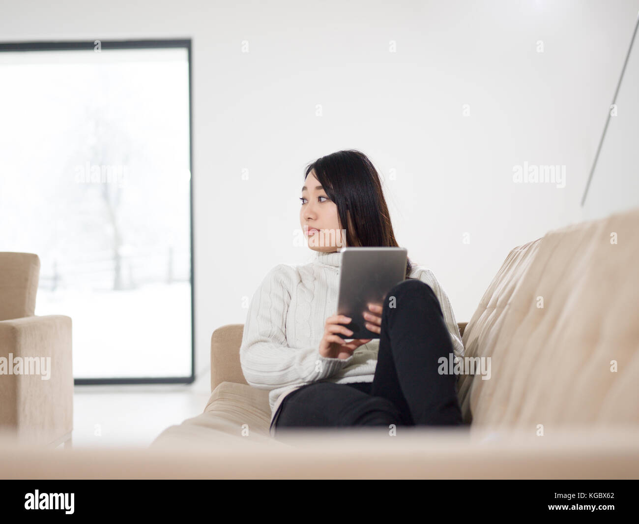 young happy asian woman sitting on sofa using Digital Tablet Stock ...
