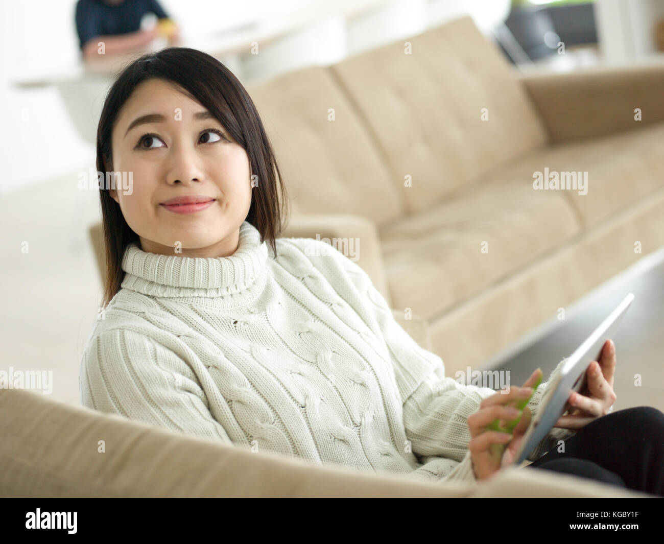 young happy asian woman sitting on sofa using Digital Tablet Stock ...