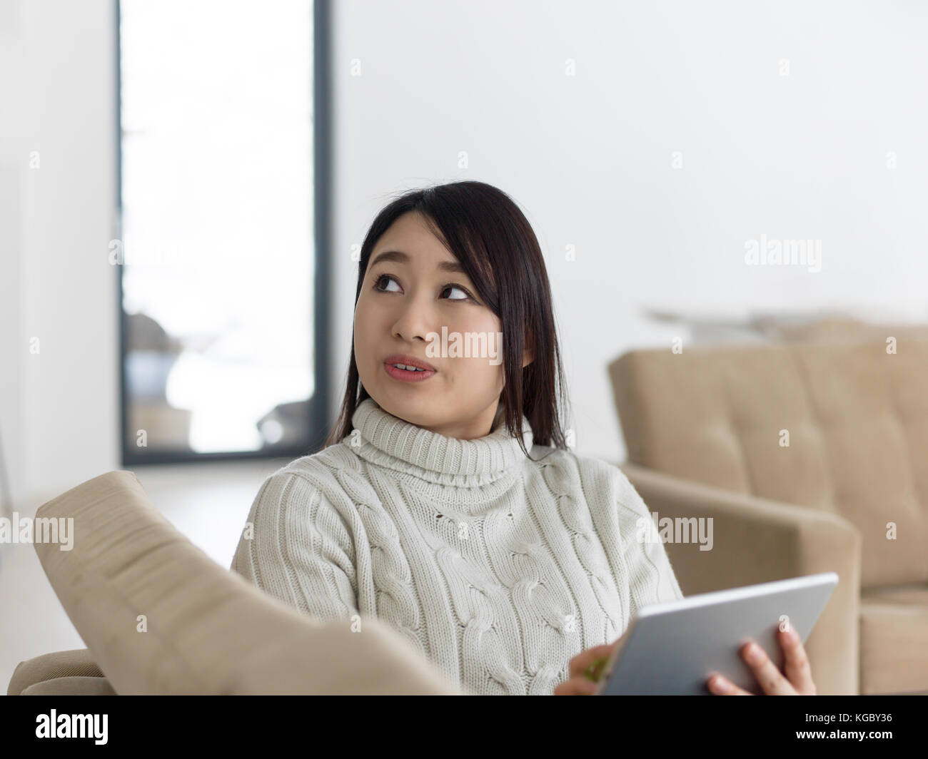 young happy asian woman sitting on sofa using Digital Tablet Stock ...