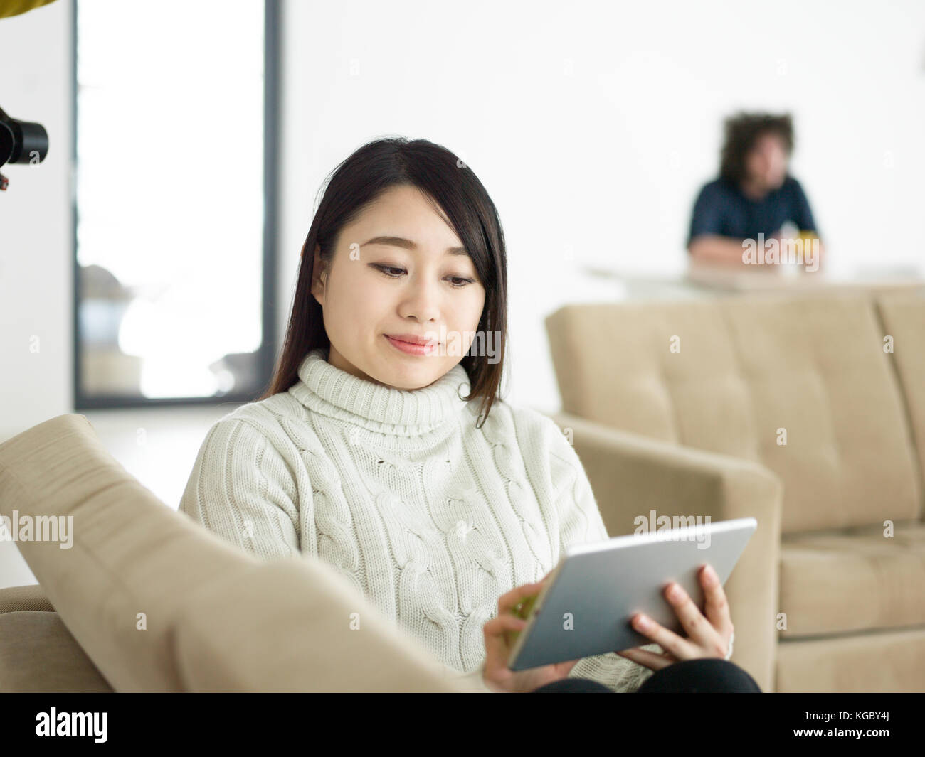 young happy asian woman sitting on sofa using Digital Tablet Stock ...