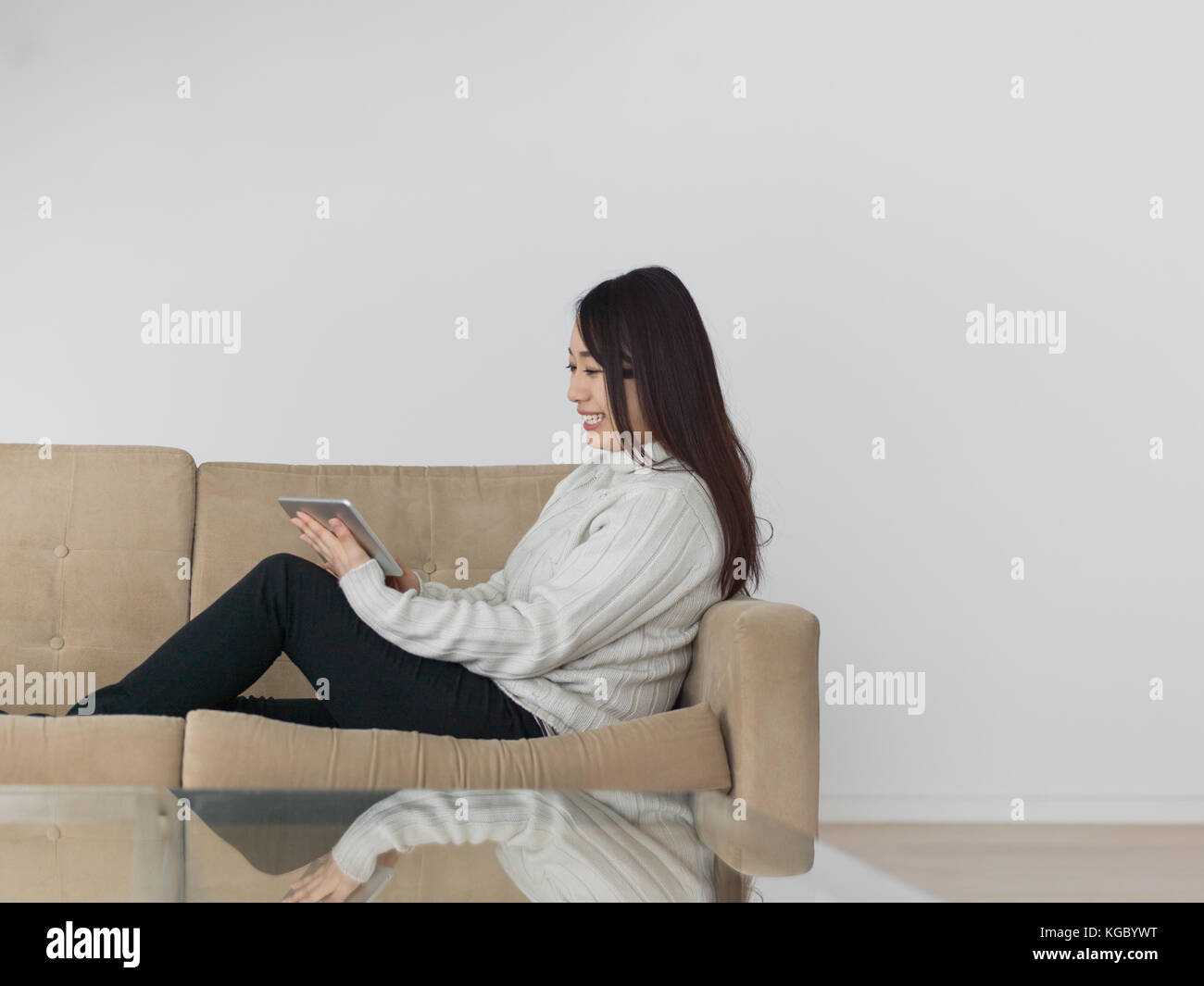 young happy asian woman sitting on sofa using Digital Tablet Stock ...