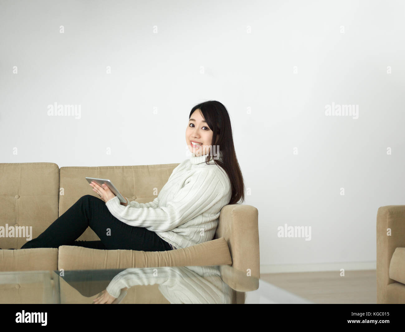 young happy asian woman sitting on sofa using Digital Tablet Stock ...