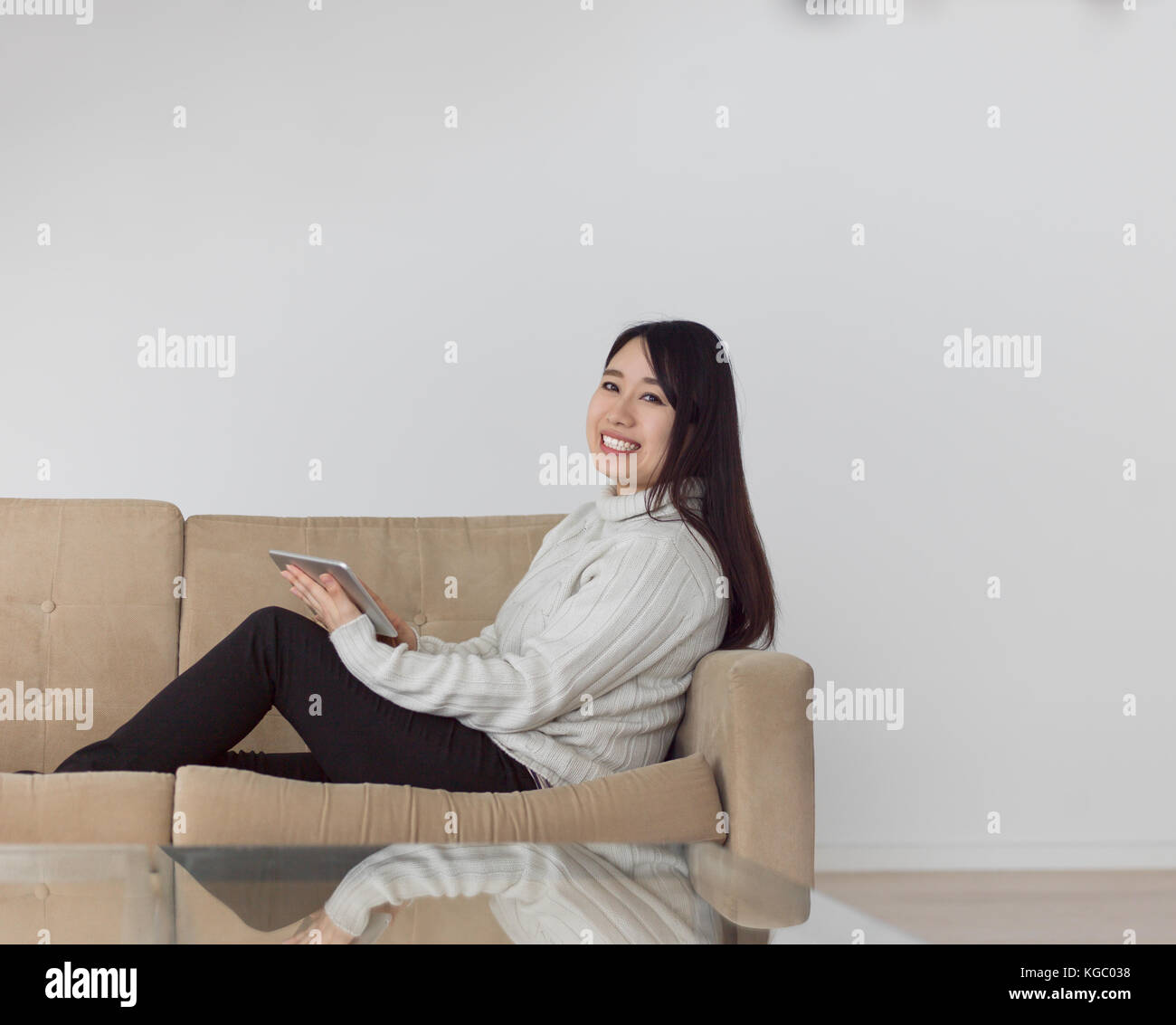 young happy asian woman sitting on sofa using Digital Tablet Stock ...
