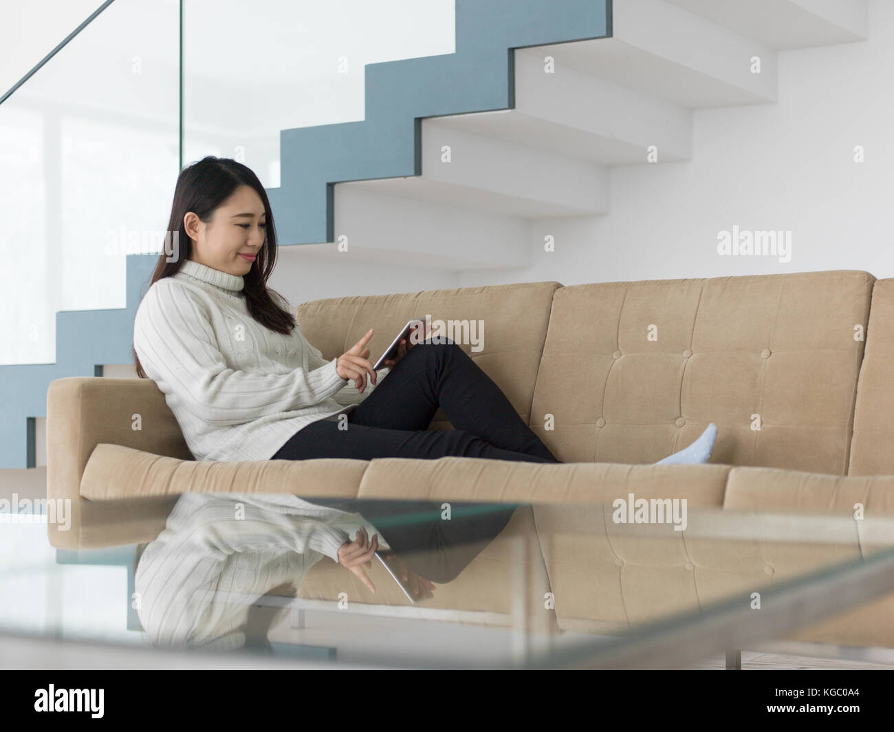 young happy asian woman sitting on sofa using Digital Tablet Stock ...