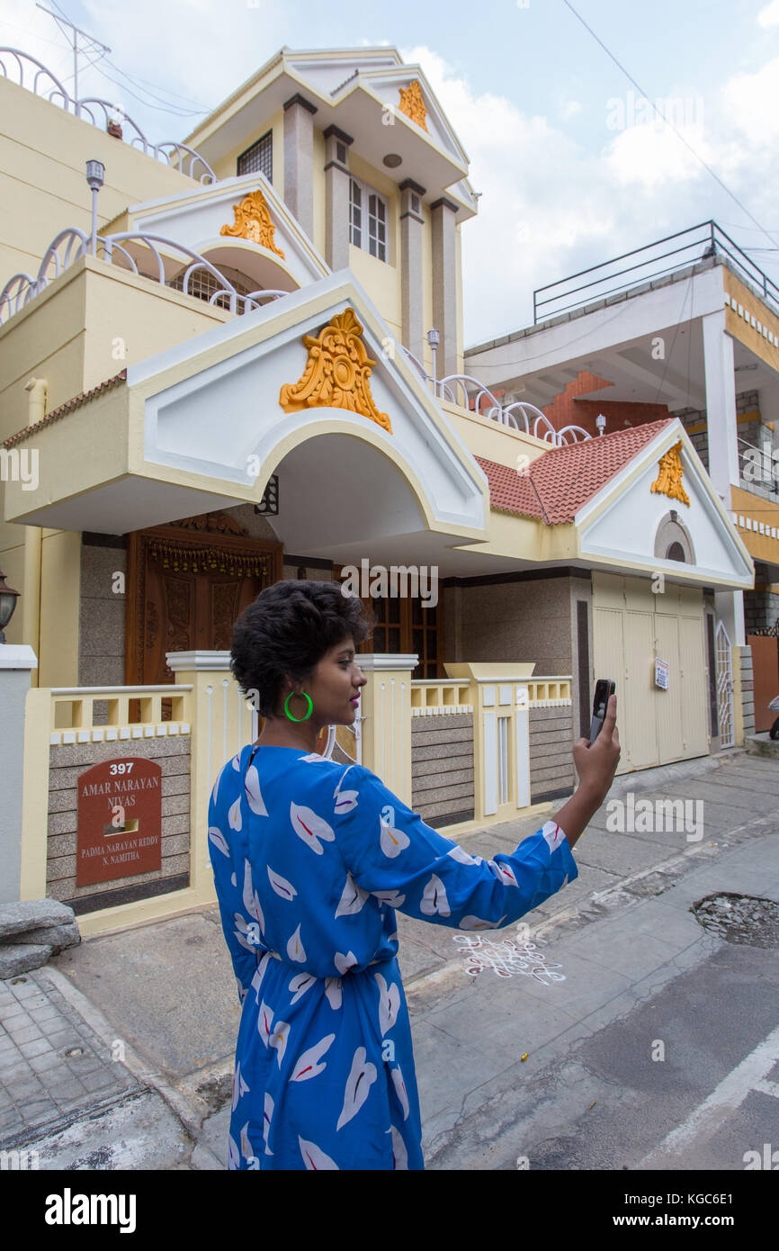 Indian girl looking at smartphone outside a house. Stock Photo