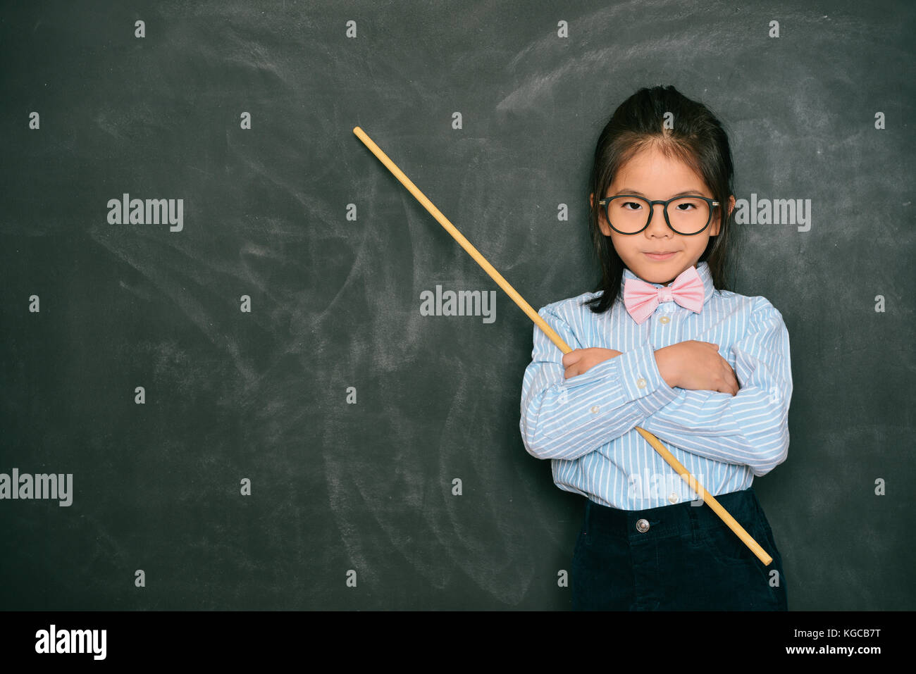 young attractive little female teacher holding stick standing in Stock