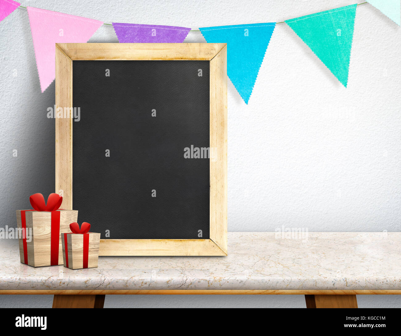 Blackboard with gift box and colorful flag banner on marble table at white wall,Leave space for display or montage of your design, Holiday new year co Stock Photo