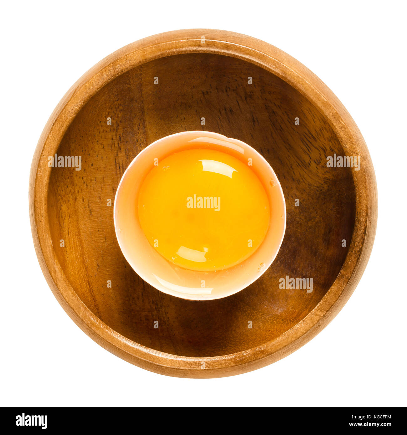 Open raw chicken egg with yolk and white in its shell in a wooden bowl. Common food and versatile ingredient used in cooking. Photo. Stock Photo