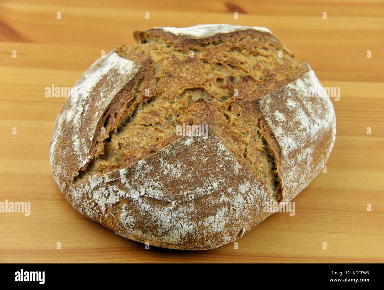 Crusty homemade artisan round wholemeal or whole wheat sourdough bread loaf made from natural wild yeast sourdough starter culture. Stock Photo