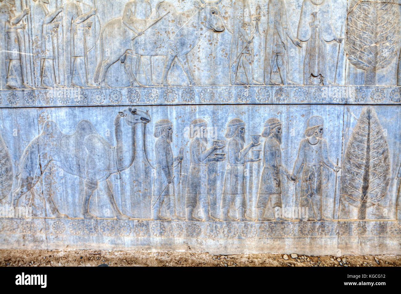 Slaves and soldiers carry gifts for Persian Emperor in Xerxes palace, stone bas-relief in ancient city Persepolis, Iran. Stock Photo