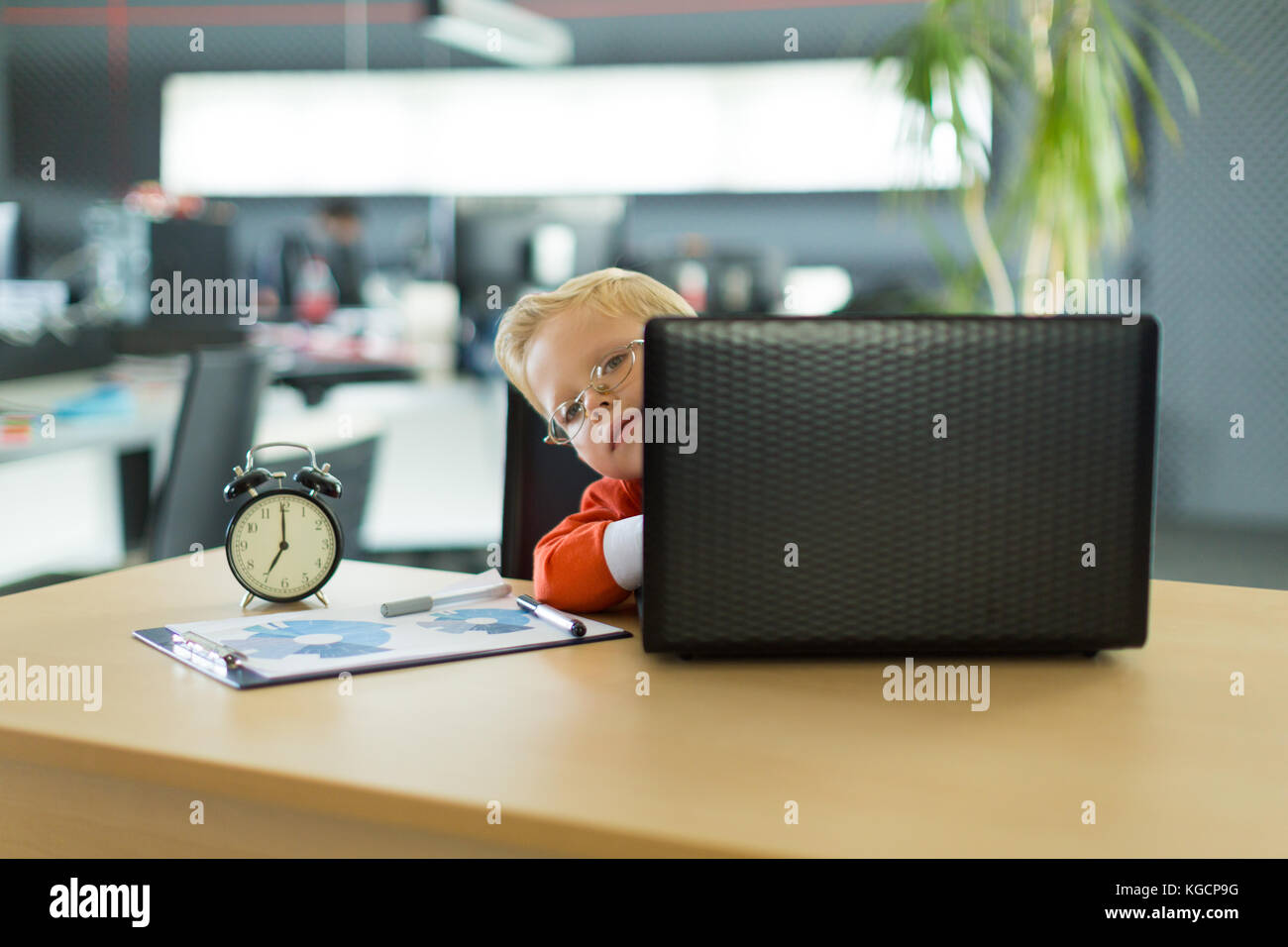 Cute boy sit at the desk in the office and uses computer Stock Photo ...