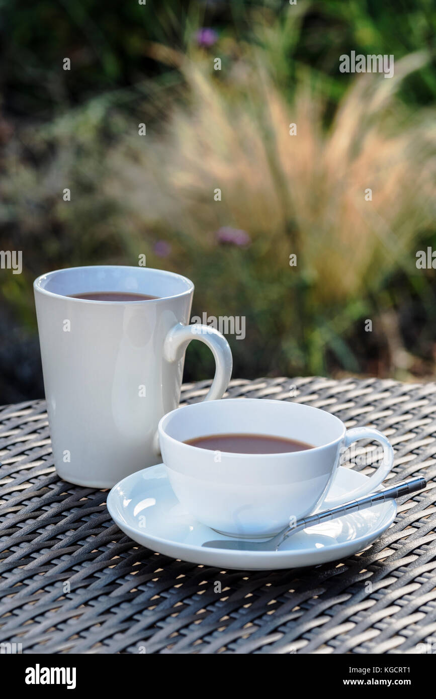 Coffe break his and hers cups, garden table. Stock Photo