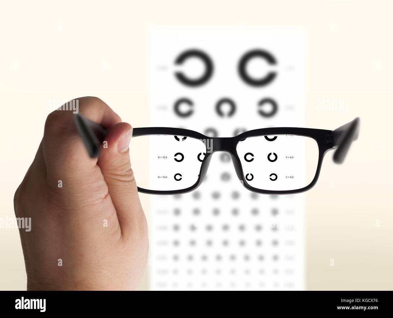 Eyeglasses in hand for eyesight. On the background of a chart test for eyes of Landolt C, isolated Stock Photo