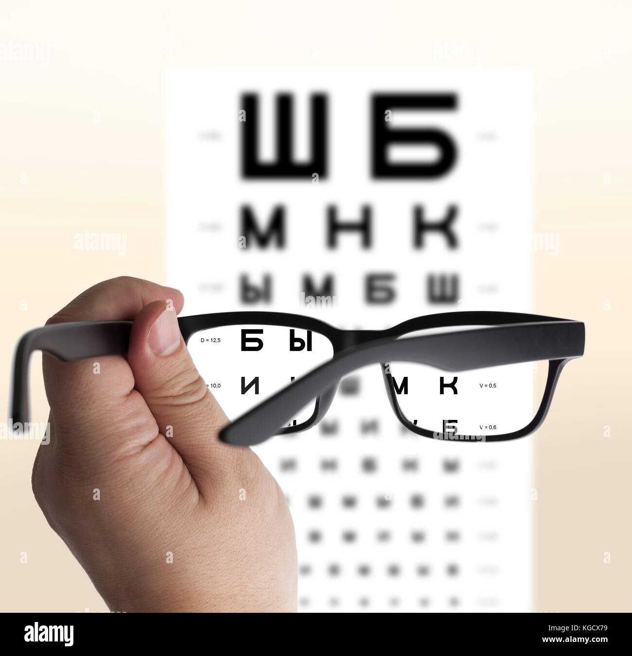 Eyeglasses in hand for eyesight Russian/Cyrillic test chart background, isolated Stock Photo