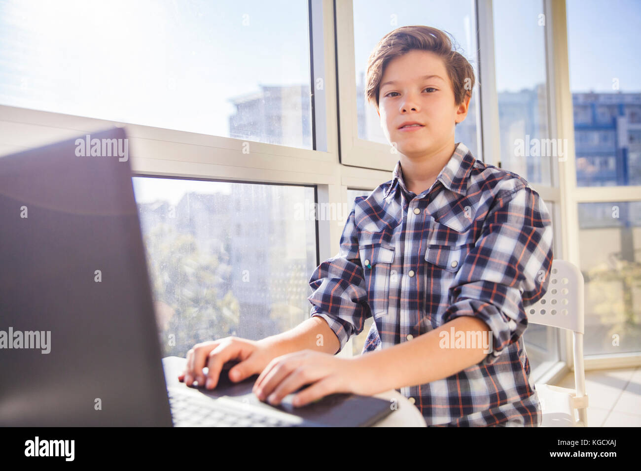 Portrait of teen boy using laptop by window Stock Photo - Alamy