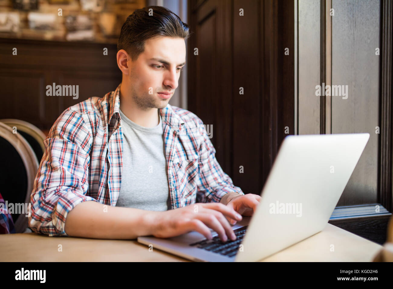 Handsome male entrepreneur typing message to content manager of website of marketing corporation on keyboard of laptop computer arranging meeting to d Stock Photo