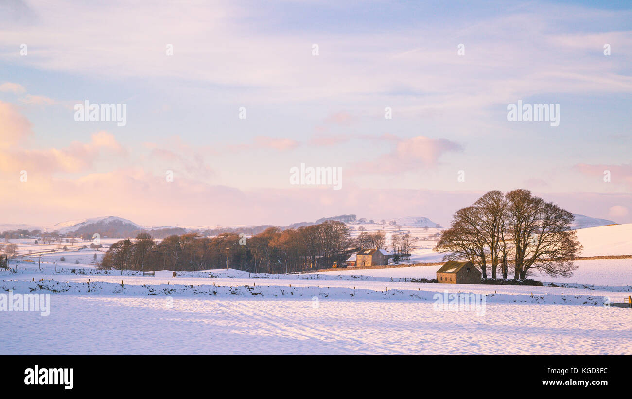 View across snowy farmland near Ashbourne at sunset on a winter evening. Stock Photo