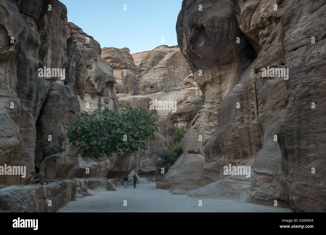 Two people walking in the Siq gorge in early morning towards the Treasury, Petra, Jordan, Middle East Stock Photo