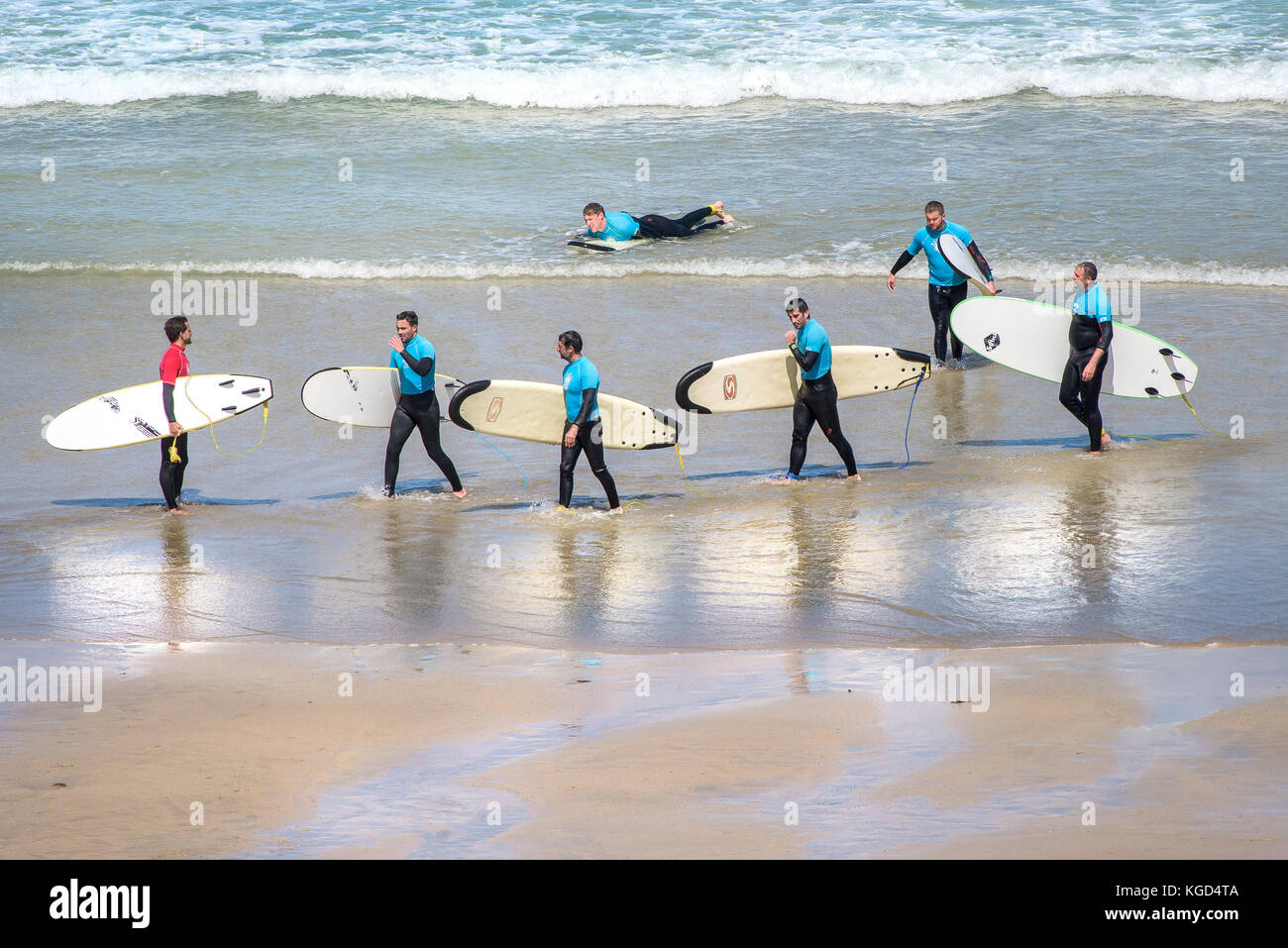 A surf instructor and his learners on a beach in Newquay in Cornwall