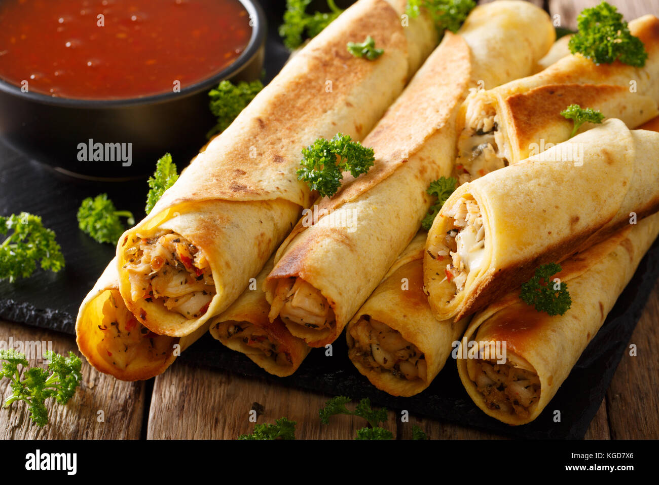 Mexican taquitos with chicken and chili sauce closeup on table