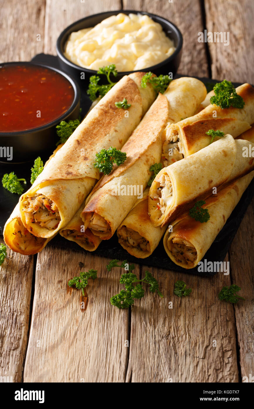 Mexican taquitos with chicken and sauces close-up on table. vertical Stock Photo