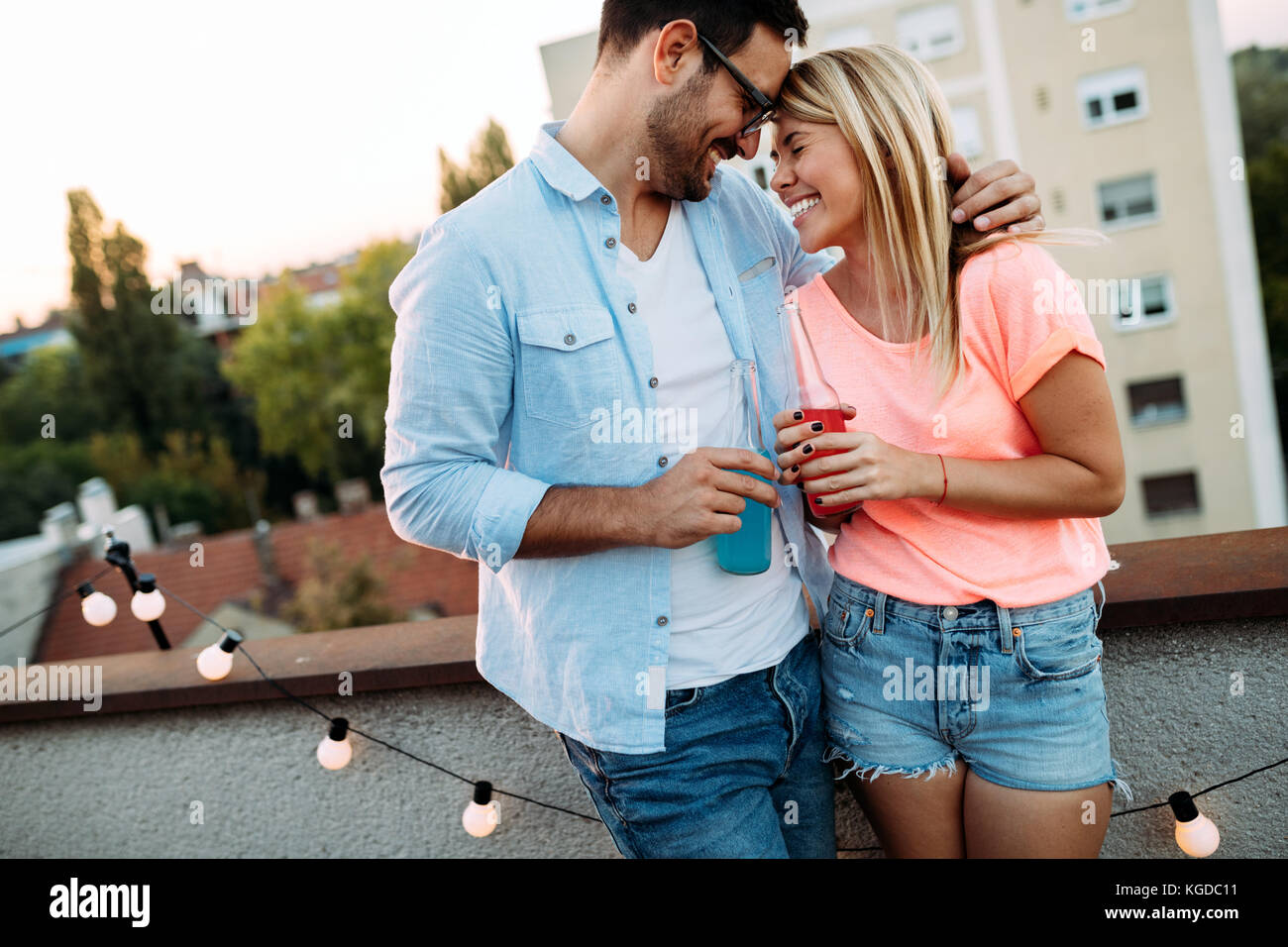 Happy young couple drinking cocktail on rooftop Stock Photo