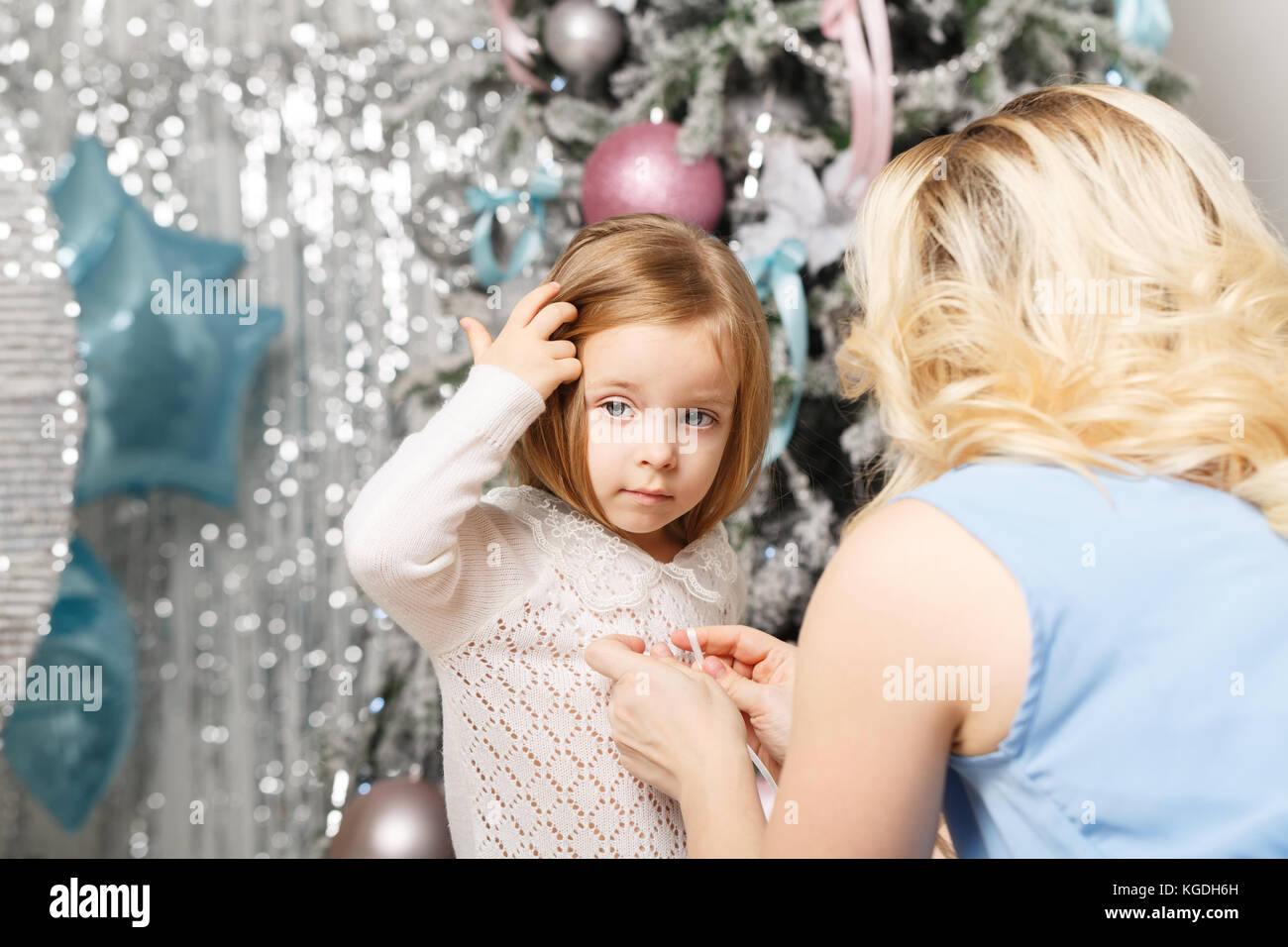Family Christmas. Mother corrects her daughter's sweater. Preparation for the holiday. Stock Photo