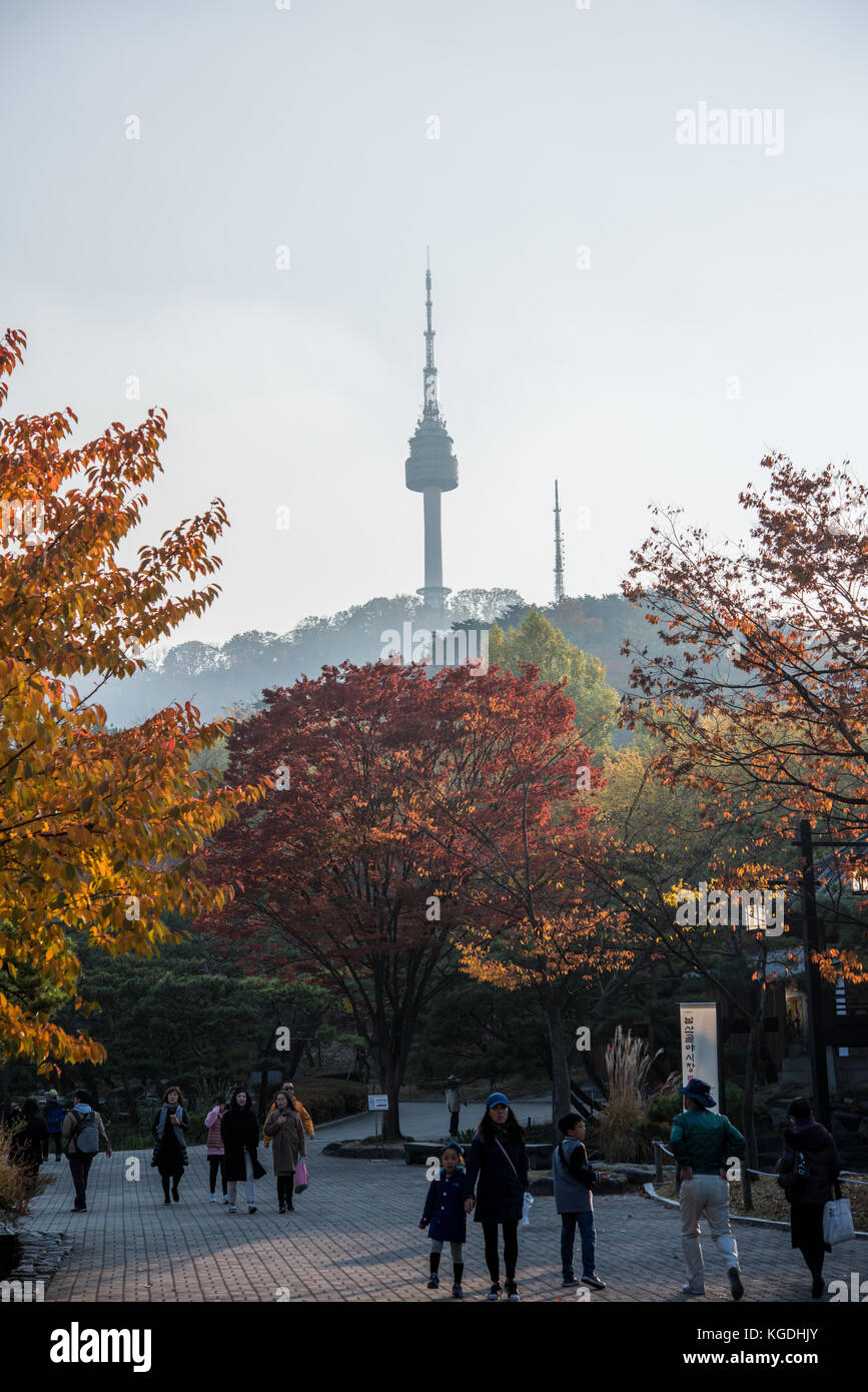 Autumn coloured trees with korean people in the foreground and a view of Seoul N Tower in the background Stock Photo
